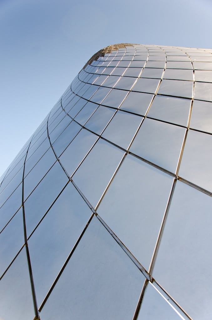 A modern skyscraper with reflective glass panels against a clear sky, showcasing contemporary architecture.