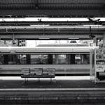 Black and white photo of a Nagano train station with vending machine and benches.