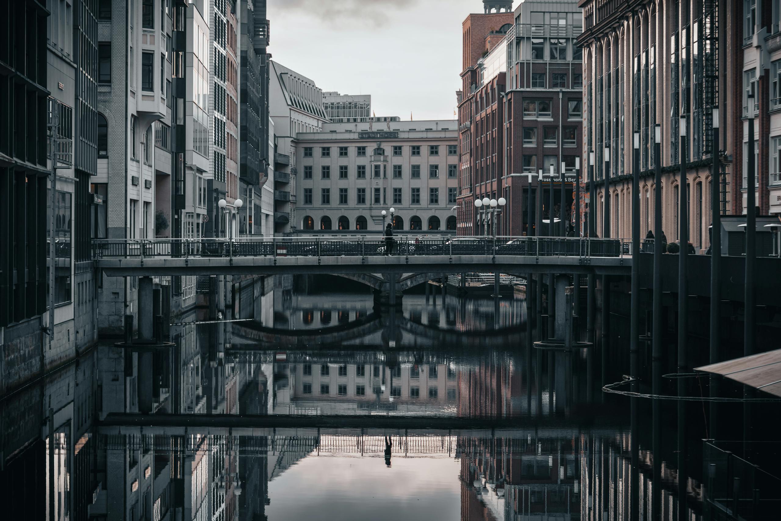 Urban scene capturing modern architecture reflecting on a calm canal in Hamburg, Germany.